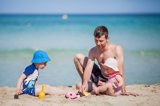 Bel papà gioca con i bambini vicino al mare.