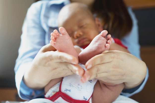 Bel piede infantile con poco bianco nelle mani della madre