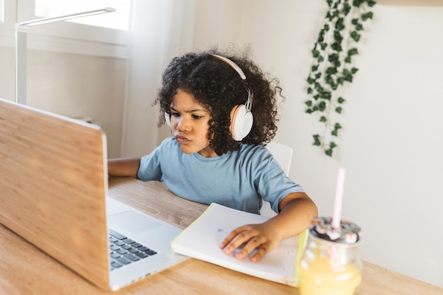 Bel ragazzino a casa con cuffie e laptop, sta ascoltando musica, mentre fa i compiti, torna a scuola, in età prescolare