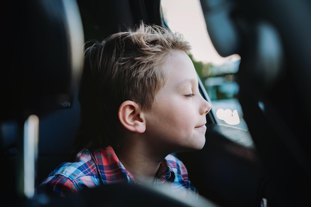 Bel ragazzo caucasico che viaggia in auto seduto nel seggiolino per bambini Concetto di ricreazione