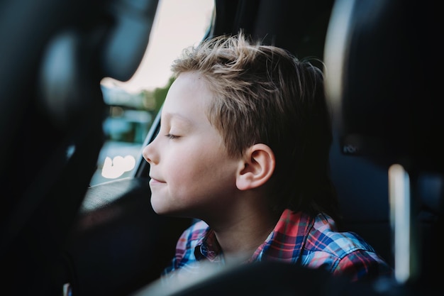 Bel ragazzo caucasico che viaggia in auto seduto nel seggiolino per bambini Concetto di ricreazione