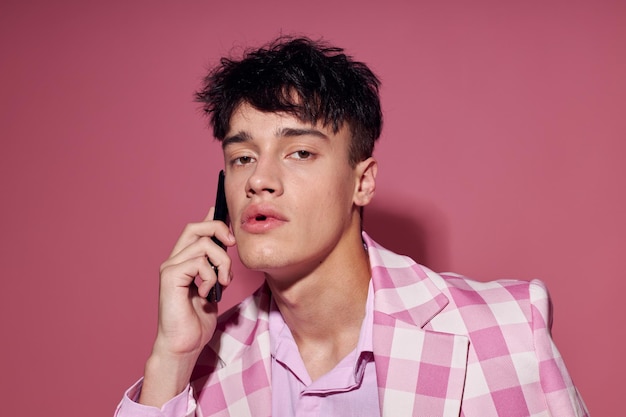 Bel ragazzo con un telefono in mano rosa blazer moda elegante modello studio