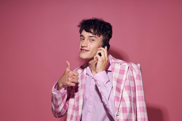 Bel ragazzo con un telefono in mano rosa blazer moda elegante modello studio