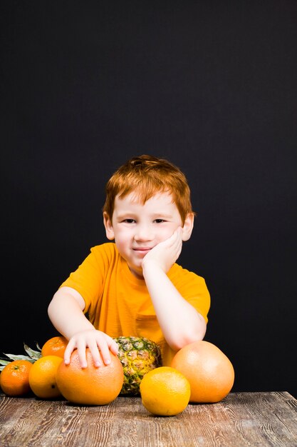Bel ragazzo dai capelli rossi con agrumi da cui puoi fare succhi o altro cibo, il ragazzo è felice e mangia agrumi