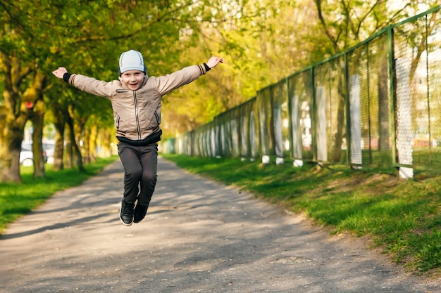 Bel ragazzo di sei anni giocando, saltando, correndo, sorridendo nel parco.