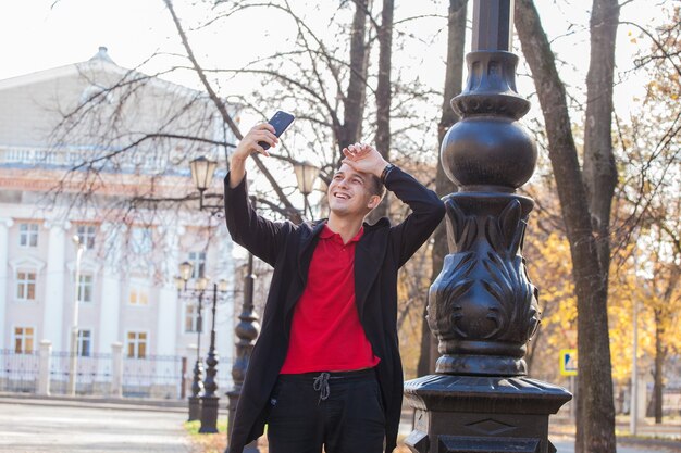 bel ragazzo durante una passeggiata nella città autunnale si fa un selfie