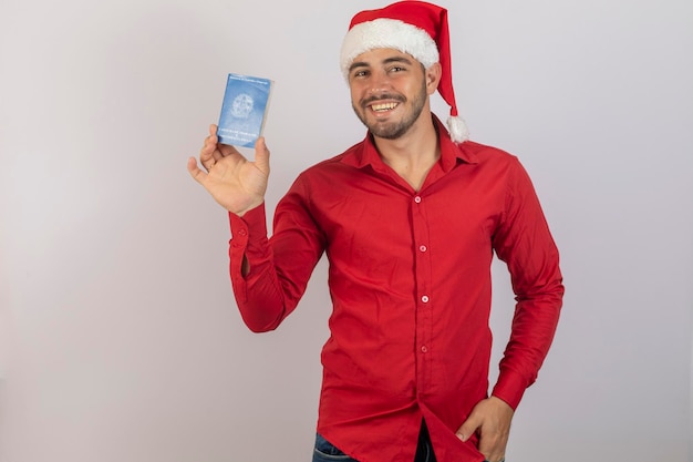 Bel ragazzo in abiti natalizi e cappello da Babbo Natale con una carta di lavoro brasiliana Concetto di lavoro temporaneo per la fine dell'anno