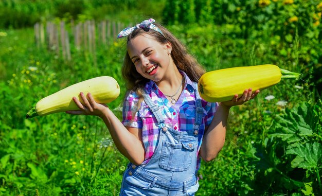 Bel ragazzo in fattoria bellezza della natura estiva bambina sul giardino agricolo con zucca crescente midollo vegetale infanzia felice retrò bella ragazza che mostra zucchine Appassionato di orticoltura