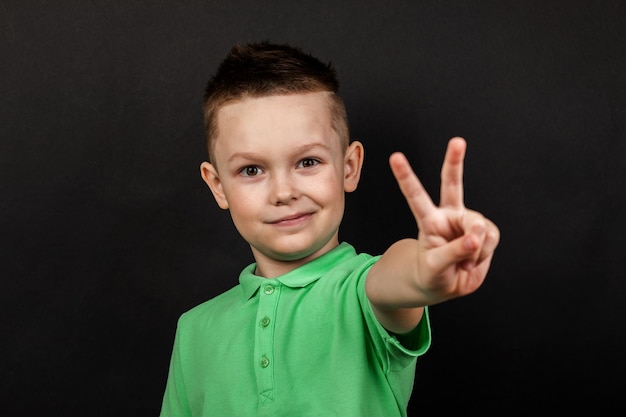 Bel ragazzo mostra il gesto della mano isolato su sfondo nero. Ritratto in studio. Emozioni maschili.