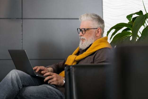 Bel regista maschio dai capelli grigi o top manager che lavora con un laptop e chatta online