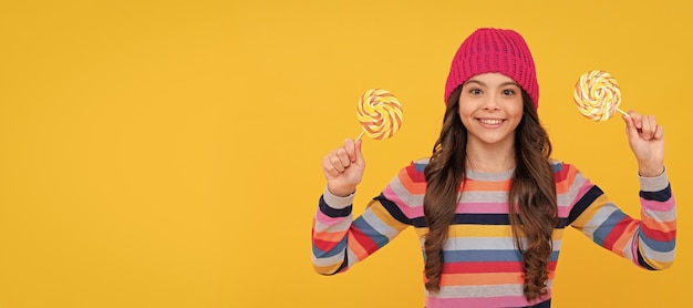 Bel sorriso hipster kid con caramelle di zucchero lecca-lecca colorate su stick caramelle negozio di caramelle Bambino adolescente con poster di dolci banner spazio per la copia dell'intestazione