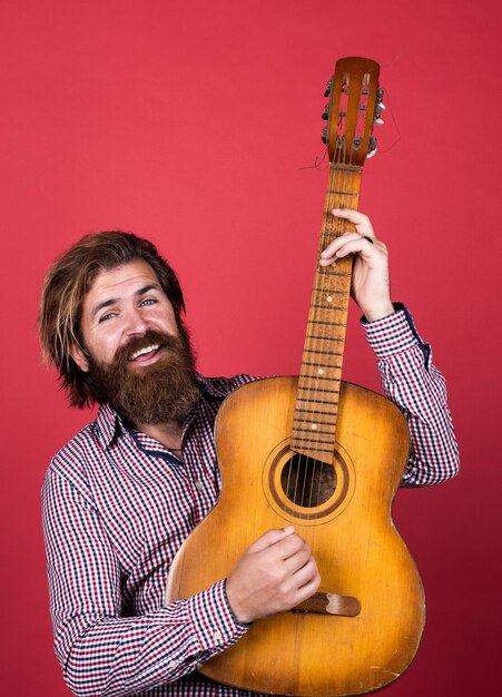 Bel sorriso maturo carismatico chitarrista maschio ragazzo con barba e baffi suonare la chitarra uomo barbuto in camicia a scacchi cantare canzone musicista musicista strumento a corda