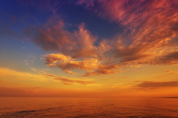 Bel tramonto, alba, sul mare, sull'oceano, sullo sfondo del cielo azzurro e delle nuvole colorate