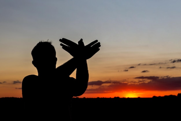 Bel tramonto con la sagoma di un ragazzo che fa il simbolo della colomba della pace