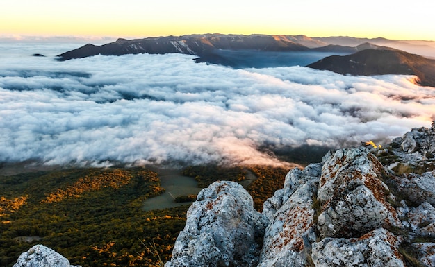 Bel tramonto dorato in montagna con nuvole basse.