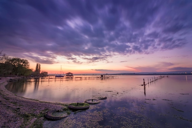 Bel tramonto sul lago con rete da pesca in acqua e vecchi pneumatici sulla spiaggia