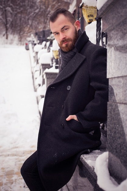 Bel uomo barbuto in giacca all'aperto. Tempo freddo della neve