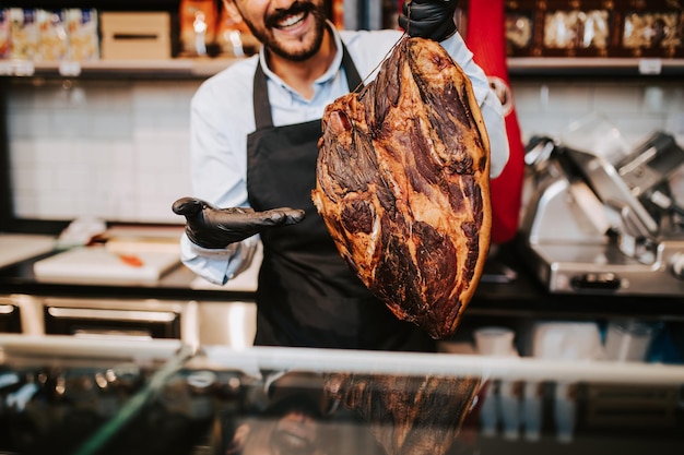 Bel venditore maschio di mezza età che lavora al supermercato o al negozio di alimentari e vende salumi e formaggi.