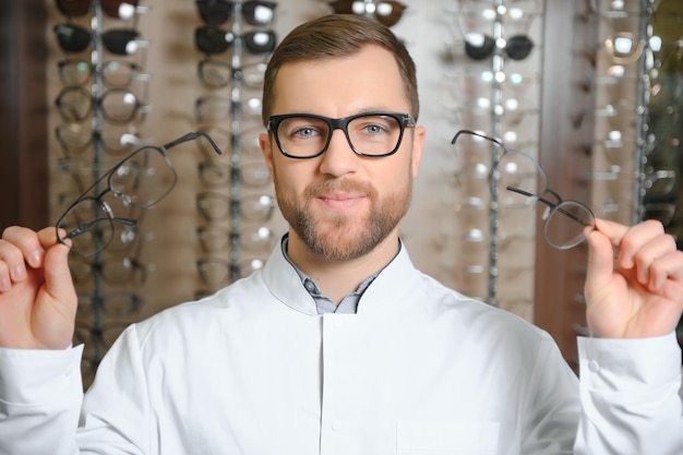 Bell'oculista che tiene gli occhiali per una prova Optometrista che offre di indossare un paio di occhiali