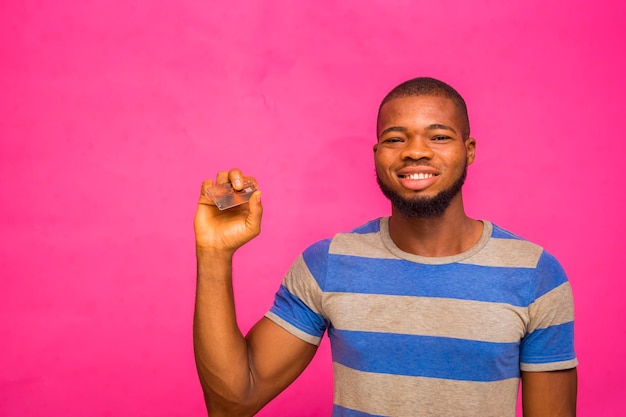 bell'uomo africano che indossa un panno di striscia isolato su sfondo rosa tenendo la carta di credito.