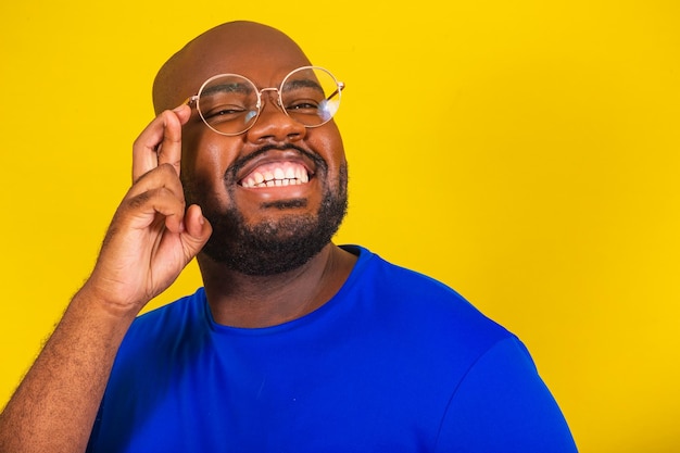 Bell'uomo afro brasiliano che indossa occhiali camicia blu su sfondo giallo segno fortunato tifo augurando voler vibrare fortuna buona fortuna disegnare