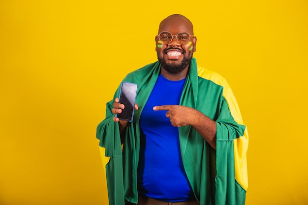 Bell'uomo afro brasiliano che indossa occhiali fan brasiliano Coppa del mondo brasiliana 2022 che punta alla pubblicità delle app di tecnologia di comunicazione dello schermo del cellulare