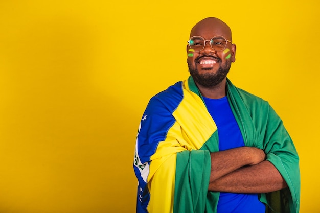 Bell'uomo afro brasiliano con gli occhiali fan brasiliano Coppa del mondo in Brasile 2022 braccia incrociate sorridente fiducia che trasmette fiducia