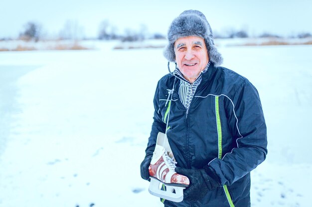Bell'uomo anziano nella soleggiata natura invernale andando a pattinare sul ghiaccio.