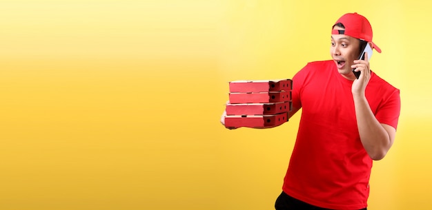 bell'uomo asiatico in berretto rosso, dando ordine italiano pizza in scatole di cartone isolato tenendo il telefono cellulare con schermo vuoto bianco bianco.