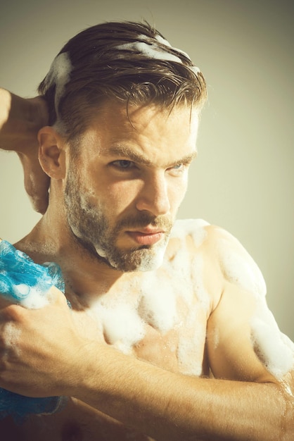 Bell'uomo barbuto che lava il corpo muscoloso con il gel per il lavaggio e la spugna con l'uomo sexy non rasato