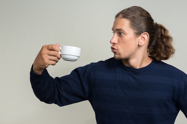 bell'uomo barbuto con i capelli lunghi contro il muro bianco