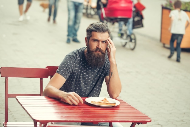 Bell'uomo barbuto con pizza al bar