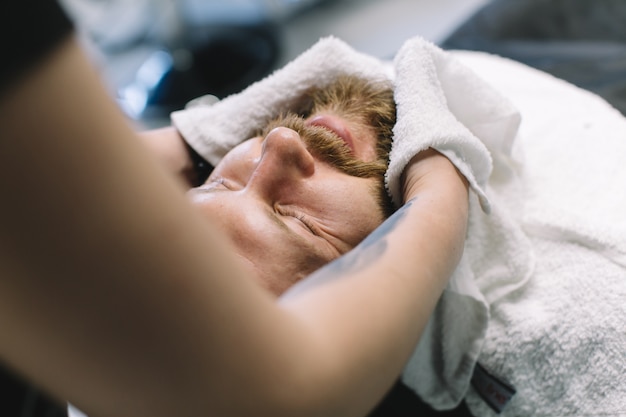 Bell&#39;uomo barbuto e con i baffi si fa la barba nel negozio di barbiere.