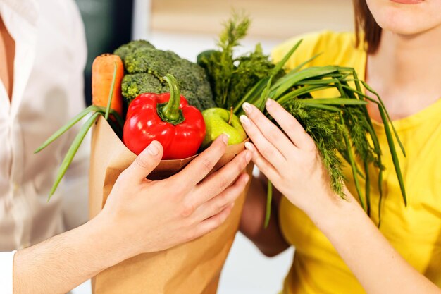 Bell'uomo barbuto e donna snella seduta al tavolo con in mano la borsa della spesa con cibo sano e nutriente