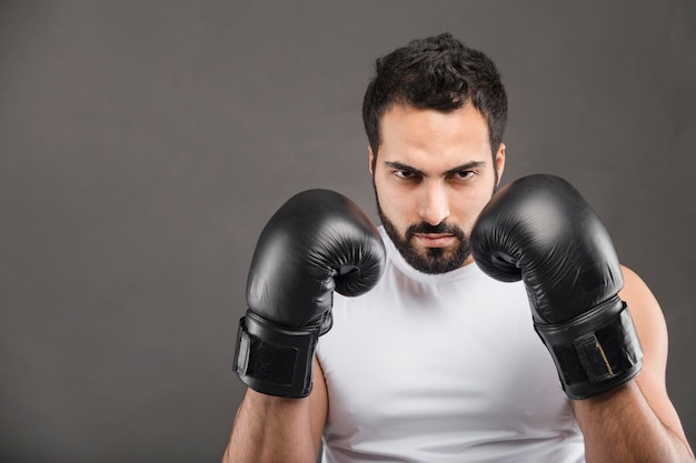 Bell'uomo barbuto in guanti da boxe e camicia bianca su sfondo grigio isolato