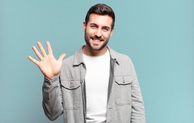 Bell'uomo biondo adulto sorridente e dall'aspetto amichevole, che mostra il numero cinque o il quinto con la mano in avanti, conto alla rovescia