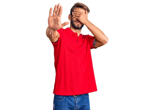 Bell'uomo biondo con la barba che indossa abiti casual che copre gli occhi con le mani e fa un gesto di stop con un'espressione triste e impaurita concetto imbarazzato e negativo