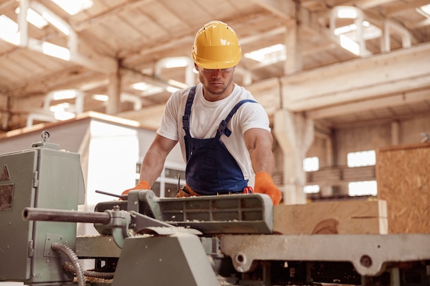 Bell'uomo carpentiere che utilizza la macchina per la lavorazione del legno in officina