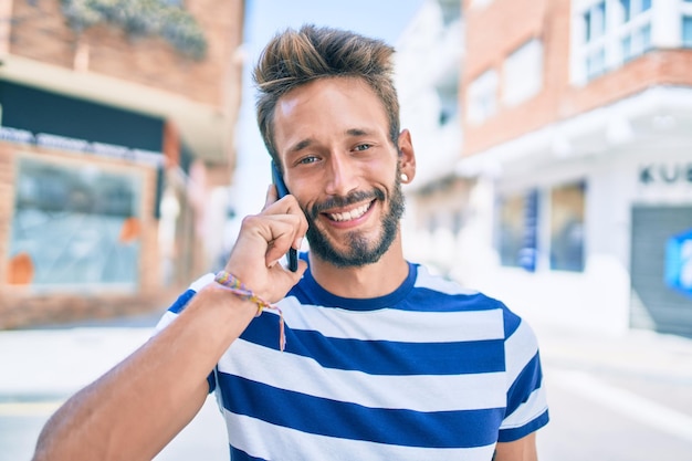 Bell'uomo caucasico con la barba che sorride felice all'aperto parlando al telefono