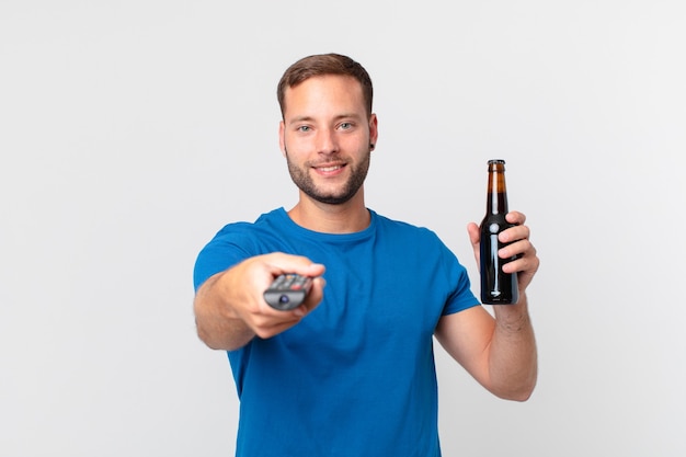 Bell'uomo che guarda la tv con una birra