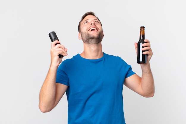 Bell'uomo che guarda la tv con una birra