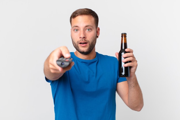 Bell'uomo che guarda la tv con una birra