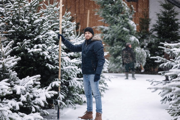 Bell'uomo che misura l'albero di natale uomo all'aperto sceglie l'abete per le vacanze invernali