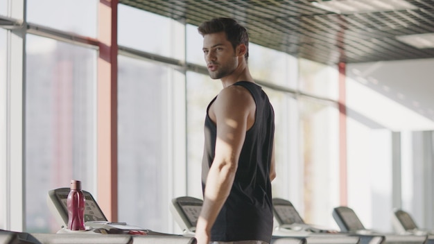 Bell'uomo che si guarda intorno nel fitness club Tapis roulant a piedi maschio macho in palestra