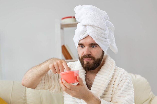 Bell'uomo che tiene in mano uno scrub rosa cosmetico per il corpo della spa della pelle e la cura della pelle per il concetto dell'uomo