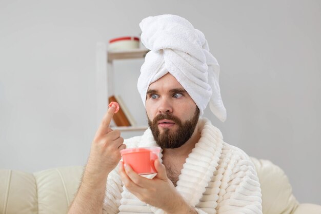 Bell'uomo che tiene in mano uno scrub rosa cosmetico per il corpo della spa della pelle e la cura della pelle per il concetto dell'uomo