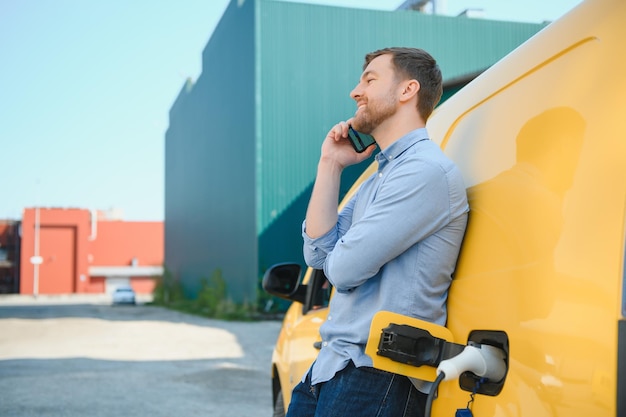 Bell'uomo che usa il telefono mentre l'auto è in carica