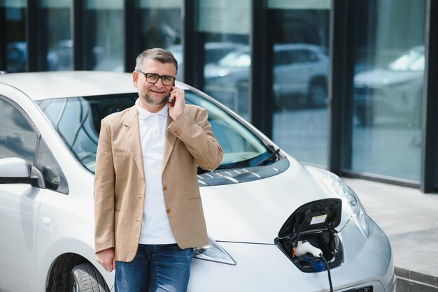 Bell'uomo che usa il telefono mentre l'auto è in carica