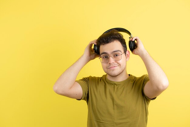 bell'uomo con gli occhiali che indossano le cuffie su giallo.