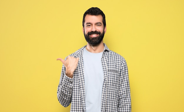 Bell&#39;uomo con la barba che punta al lato per presentare un prodotto